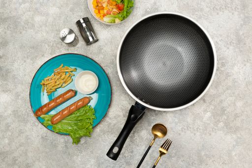 A flat lay of a frying pan with cooking spices and already made lunch on the table