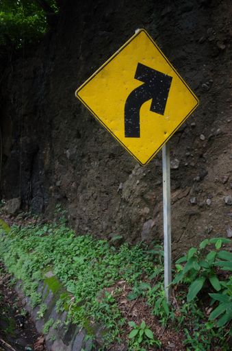 A closeup shot of a yellow turn sign on a road