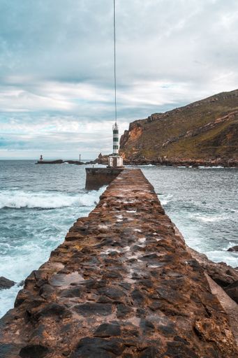 A vertical shot of a beacon at a stone pier in Pasajes San Pedro, Gipuzkoa, Spain