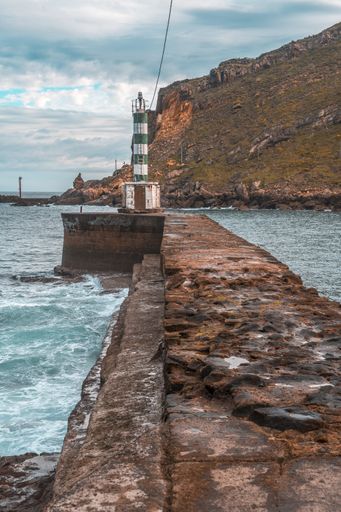 A vertical shot of a beacon at a stone pier in Pasajes San Pedro, Gipuzkoa, Spain