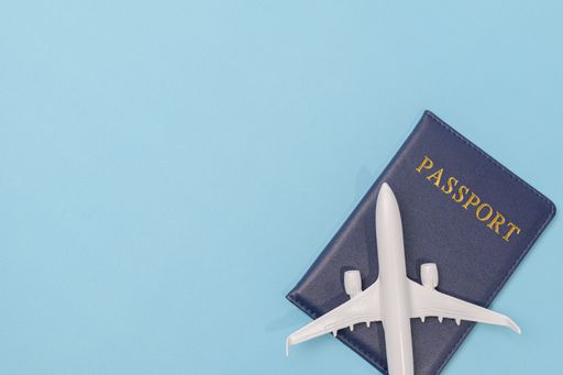 A top view of a passport and airplane isolated on blue background - travel concept