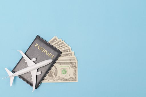 A top view of passport, airplane isolated on blue background - travel concept