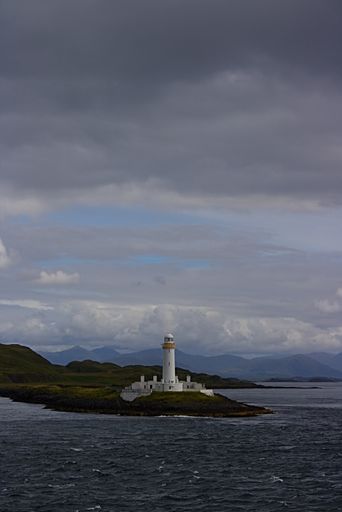 A vertical shot of Scotland isle of mull coast and lake lighthouse under the blue cloudy sky