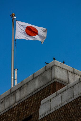 A low-angle shot of the Japanese flag winding against the blue sky