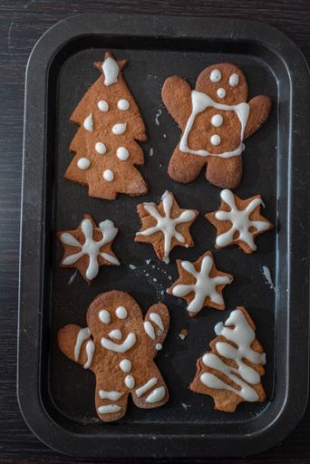 A vertical top view of homemade gingerbread cutout cookies in a black roaster
