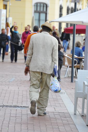 A selective focus shot of a male with a hat seen from behind walking down the street