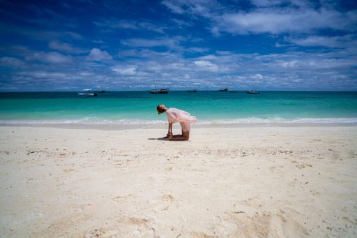A happy carefree woman doing yoga on the beach. Zanzibar, Tanzania