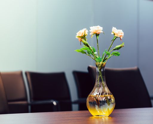 A beautiful glass vase with roses on a wooden office table