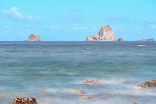 Long exposure shot of volcanic shore and seascape on El Hierro, with Roques de Salmor at the horizon, Atlantic Ocean, Canary Islands, Spain.