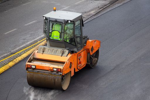 Asphalt roller working on pavement of a road. High angle view