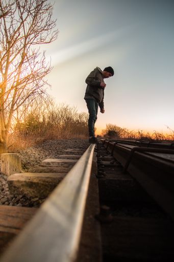 A vertical shot of a Caucasian (White) man standing on train tracks