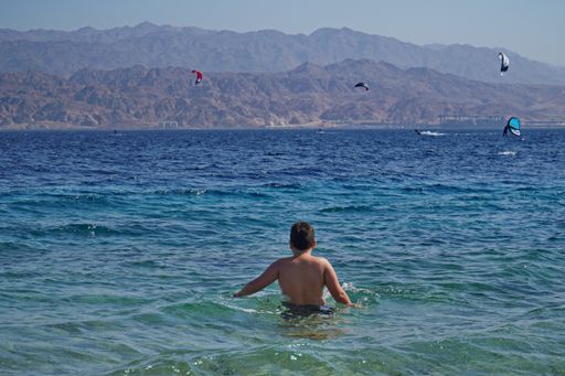 The wind surfing in the sea of Eilat, Israel with the city of Aqaba in Jordan in the background
