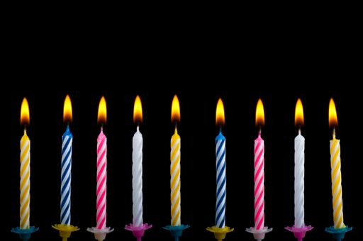 A closeup shot of birthday color candles with fire on a black background