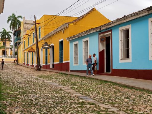A wide shot of people near colorful buildings on a cobblestone street in Trinidad, Cuba
