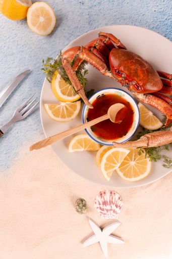 The freshly cooked crabs on a wooden tray served with red sauce and lemon slices