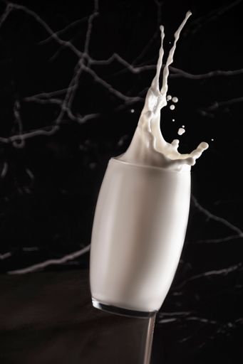 A stop motion shot of a glass full of milk on the black marble surface