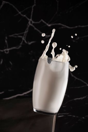 A stop motion shot of a glass full of milk on the black marble surface