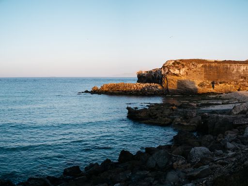 A rocky seashore in Tarifa with calm waves under a blue sky in the afternoon on a sunny day