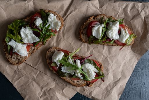 An overhead shot of freshly baked country bread sandwiches with mozzarella, tomatoes and arugula