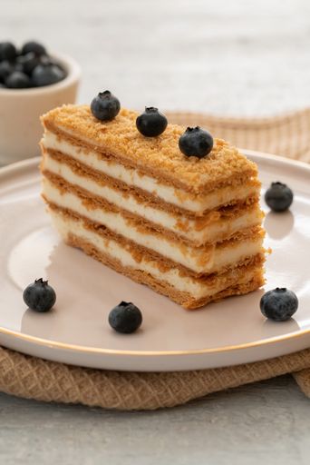 A slice of a cake topped with fresh blueberries on a white plate