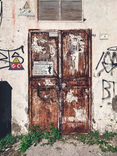 A vertical shot of rusty metal doors of an abandoned electric station