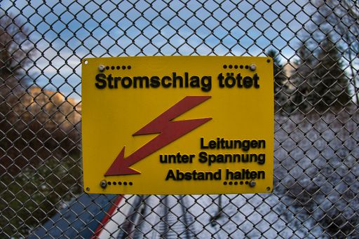 A closeup shot of an electricity warning sign with inscriptions in german