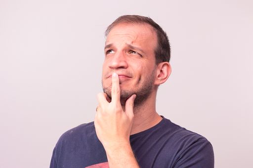 A close-up shot of a young man looking up with a hand on his chin