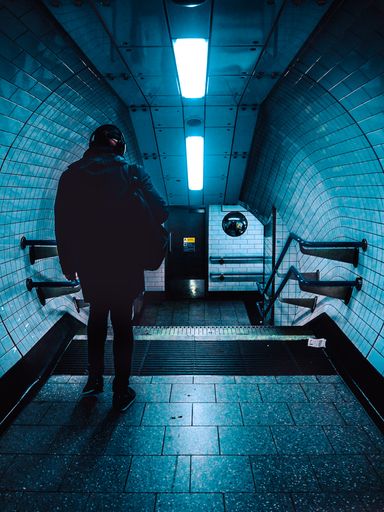A vertical shot of a human walking down by an underground tunnel