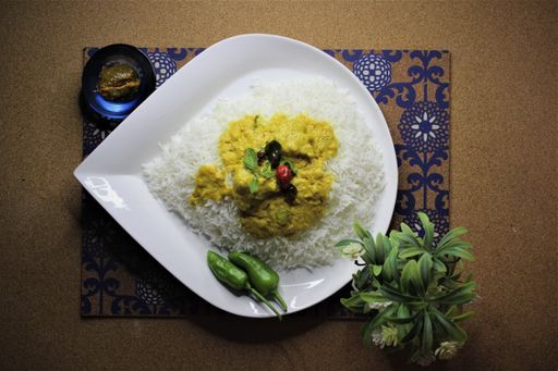 A top view of boiled rice on the plate with green peppers seasoned with a tasty sauce