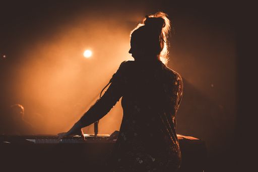 A silhouette of a woman playing piano on stage