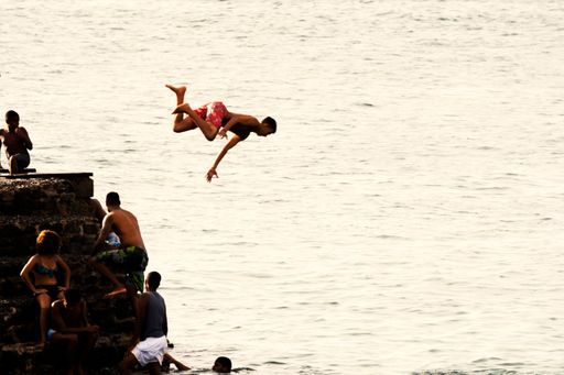 The Young people jumping into the sea from the Fort of Santa Maria pier in Porto da Barra.