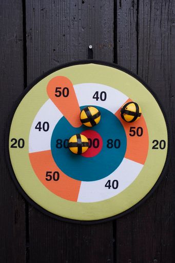 A vertical shot of fabric dart target with sticky balls hanging on the wall