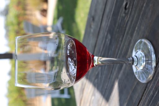 A vertical closeup shot of a glass of zinfandel red wine at a winery