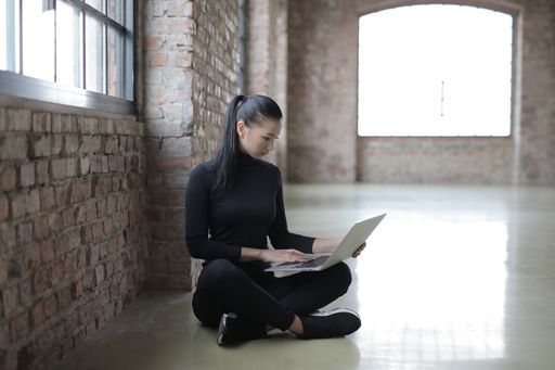 A shot of an attractive female sitting on the floor working with laptop
