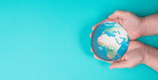 Hands holding planet earth in front of a turquois background, environmental issues, earth day