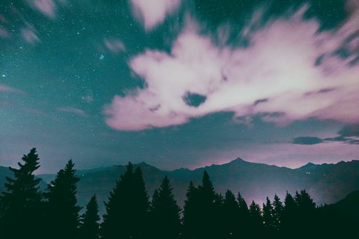 A Milky way Stars in the night sky with silhouettes of mountains in the background