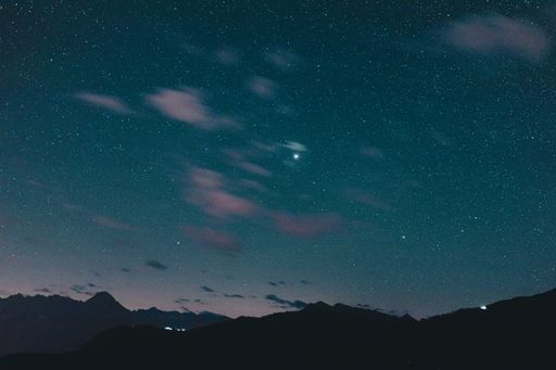 A Milky way Stars in the night sky with silhouettes of mountains in the background