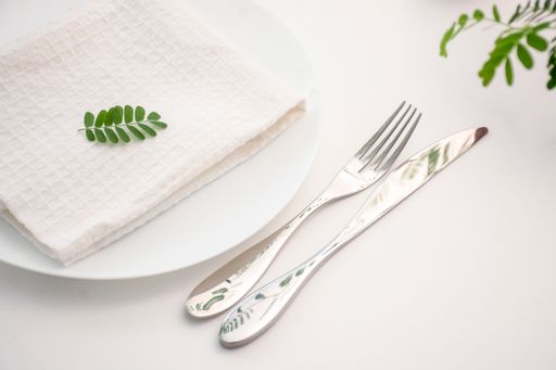 A closeup of a plate with a napkin, a fork, and a knife on the table