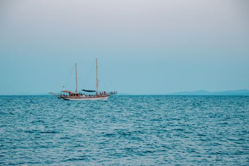 A single boat in the middle of a sea under a blue cloudless s