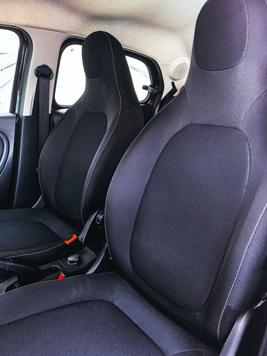 A vertical shot of the black seats inside a modern car with a white ceiling