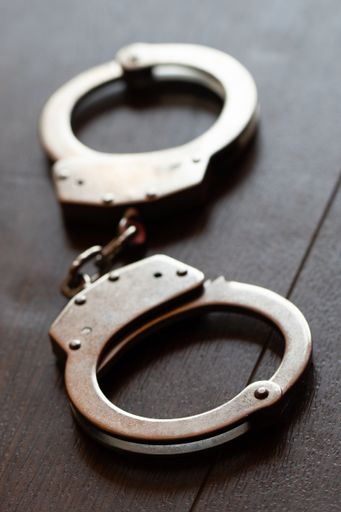 A vertical high angle shot of metal handcuffs on a wooden surface