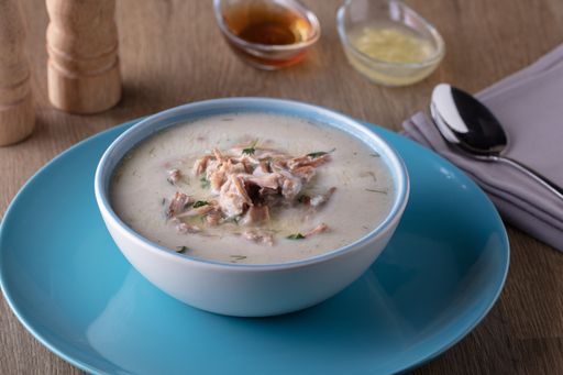A high angle shot of a bowl of delicious cream soup and some spices on a wooden surface