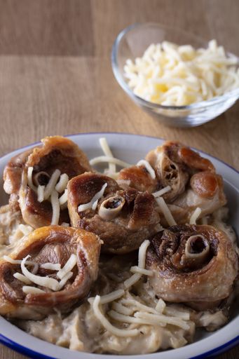 A vertical high angle shot of a plate grilled mushrooms a bowl of cheese on a wooden table
