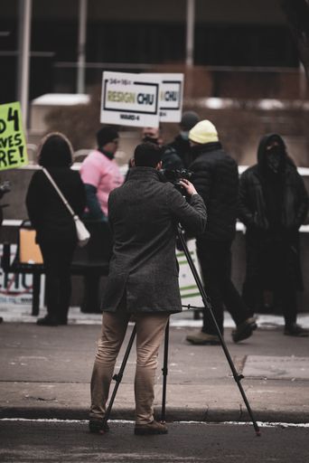 A vertical shot of a cameraman filming a protest in Canada