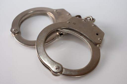 A high angle shot of metal handcuffs isolated on white surface