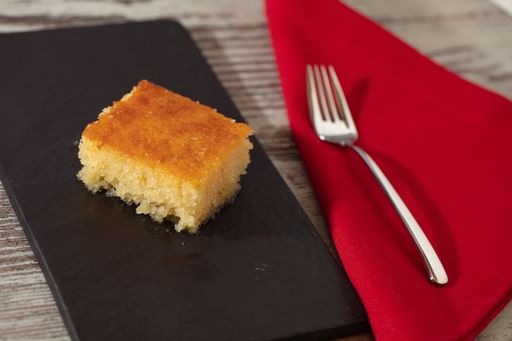A high angle shot of a piece of delicious cake and fork on a red napkin on a wooden surface