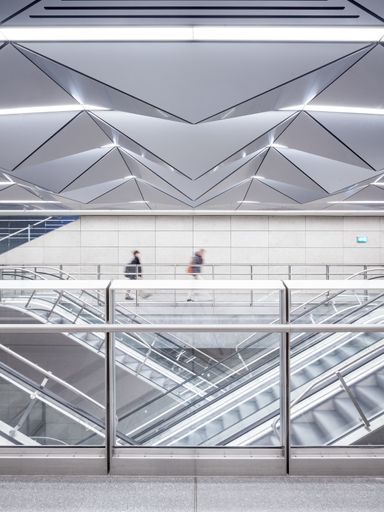 A view of people rushing and taking the escalator in a building with modern architecture