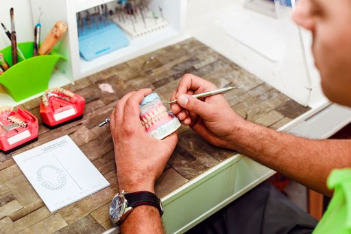 The dentist preparing artificial teeth with a special tool