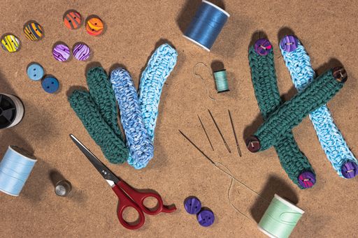 A high angle shot of small knitted belts and colorful sewing supplies on the table under the lights
