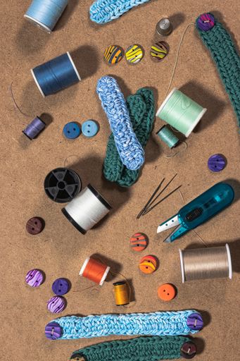 A vertical high angle shot of small knitted belts and colorful sewing supplies on the table